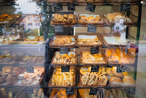 Large selection of pretzels and other baked pastries arranged nicely and on display in a bakery shop window.