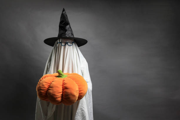 istock Ghost with hat, glasses and holding pumpkin stuffed animal. 1338190477