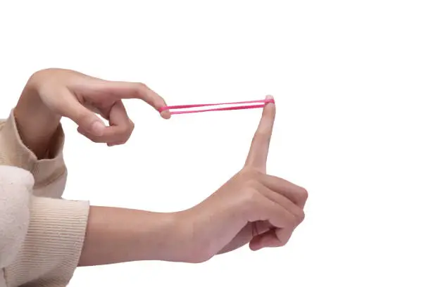 Close up of girls hand pulling rubber band ready to shoot, isolated on white background