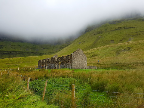 Ruined building in Gleniff Horseshoe drive, County Sligo, Ireland, view during low clouds.