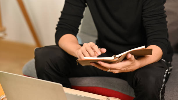 istock Cropped shot man reading a book on sofa at home. 1338191271