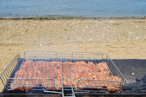 Barbecue on the beach. Marinated meat is fried on hot coals, soaked in fragrant smoke. Selective focus.