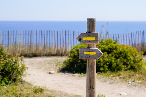 yellow sign arrow markings for walking path hiking trails pathway in nature beach coast