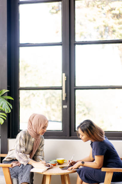 istock Two Girls Doing Home Work and Discussion in a Coffee Shop. 1338205250