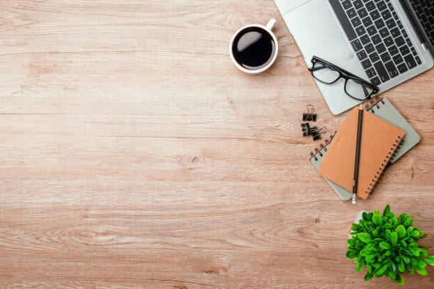 istock Work from home. desk office with laptop, blank notepad, coffee cup and pen on wood table. Flat lay top view copy spce. 1338211515