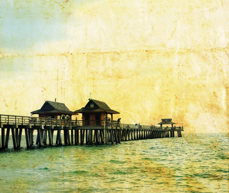 Vintage travel shot of fishing pier with grunge paper appearance.