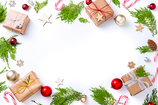 Top view of a large group of christmas gifts and ornaments on a frame shape with copy space at the center of the image on a white background