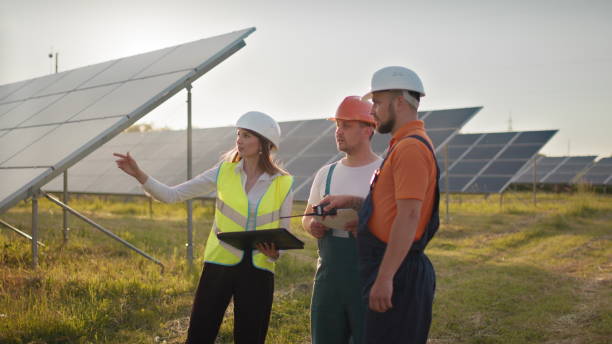 istock Three solar energy specialists at a solar power facility. Professional engineers discuss innovative project. Team of industrial technicians in solar park. Construction of solar power plant 1338214926