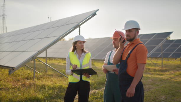 istock Three solar energy specialists at a solar power facility. Professional engineers discuss innovative project. Team of industrial technicians in solar park. Construction of solar power plant 1338214930