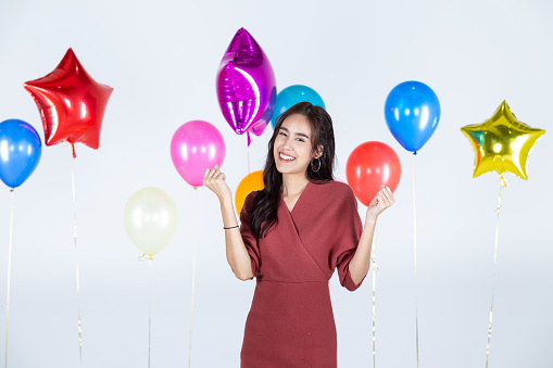 Asian women have enjoy during Christmas and New Year 2022. On a white backdrop and multicolored balloons