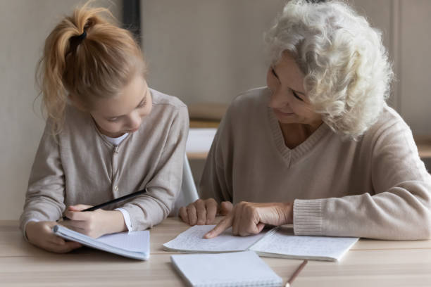 istock Caring grandmother help granddaughter with homework assignment 1338215600