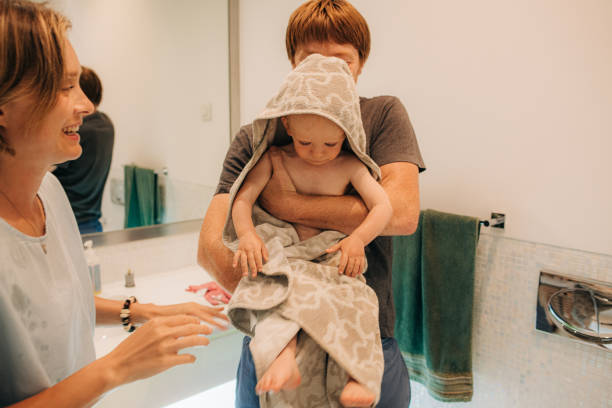 istock Happy parents wrapping their daughter in towel 1338220934