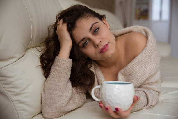 istock Beautiful girl lying on the sofa and drinking coffee 1338221691