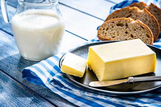 butterstange, milchglas und brot auf blauem tisch - butter bread breakfast table stock-fotos und bilder