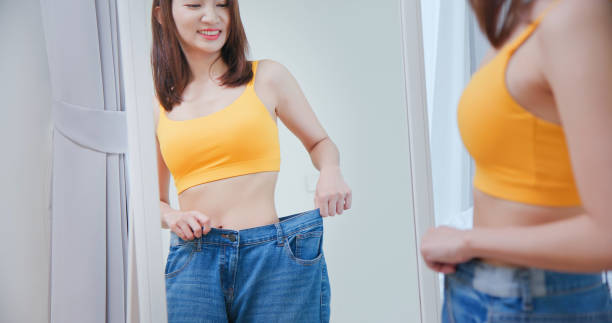 女性は彼女の大きなジーンズを見せる - abdomen women waist slim ストックフォトと画像