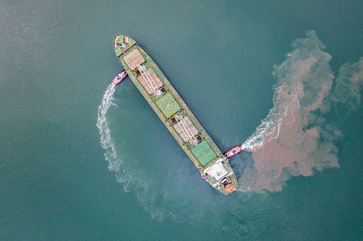 Top view of Freight Ship approaching port with tugboat.
