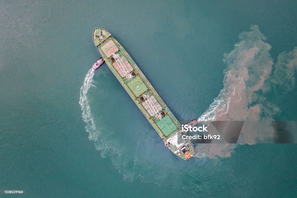 Top view of Freight Ship approaching port with tugboat. Harbour tugboat guides a cargo ship into the harbour of Samsun - Turkey - Taken with DJI Mavic 2 Pro, You can see more shipping concept images in my portfolio. Aerial drone view of a container ship nearing port with the assistance of a tugboat Pushing Stock Photo