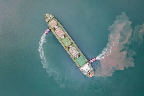 Harbour tugboat guides a cargo ship into the harbour of Samsun - Turkey - Taken with DJI Mavic 2 Pro, You can see more shipping concept images in my portfolio. Aerial drone view of a container ship nearing port with the assistance of a tugboat