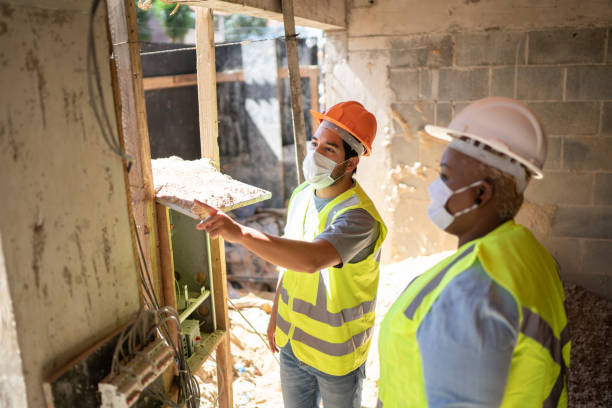 istock Electrician and construction worker having a meeting at a construction site - wearing protective face mask 1338236485