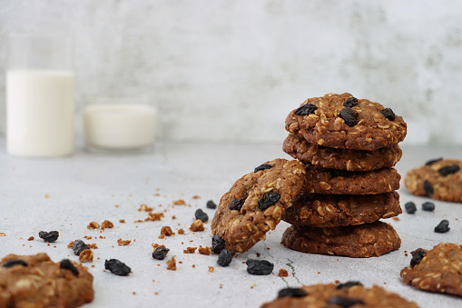 Stock photo showing a close-up view of heap of freshly baked, homemade oat and raisin biscuits on a marble effect surface.