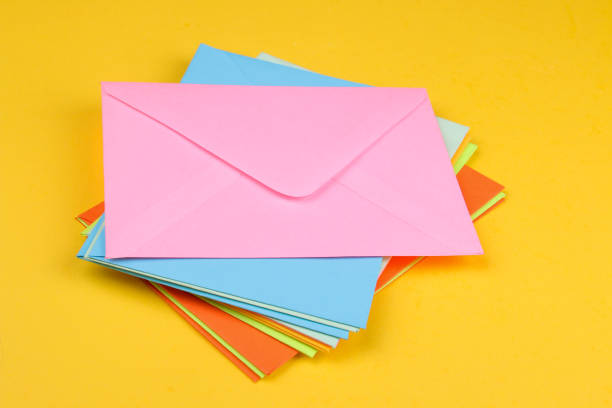 istock Multicolored postal envelopes stacked on a bright yellow background concept of mail or delivery 1338246288