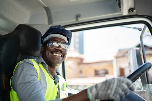 Portrait of a truck driver inside the truck at a construction site