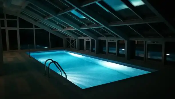 An indoor swimming pool at.night, with nobody around
