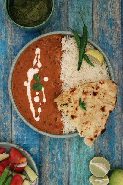 imagen del tazón azul que contiene comida casera de dal makhani (lentejas negras y curry de frijol rojo), servida con arroz blanco y pan plano de naan, rodajas de limón, chiles verdes, ensalada de acompañamiento, salsa de chutney de cilantro de menta, f - fruit tomato vegetable full frame fotografías e imágenes de stock