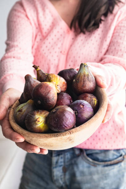istock Woman holding a bowl with fresh figs 1338261879