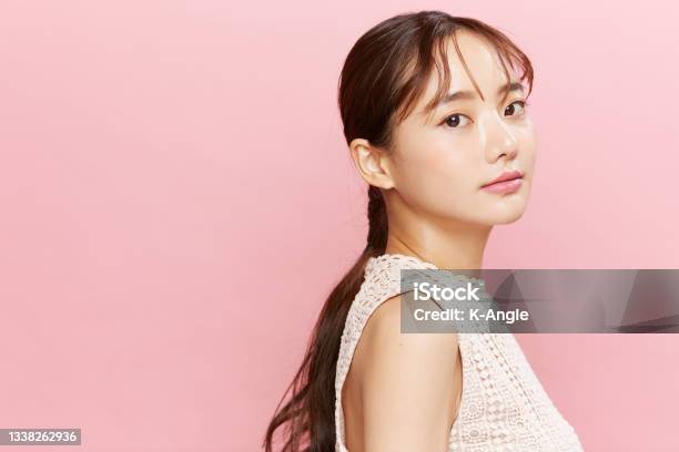ピンクの背景に服を着て若いアジアの女性の美しさの肖像画