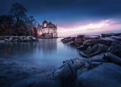 Montreux, Switzerland - Dec 04, 2019: Illuminated Chillon Castle and Lake Geneva at sunset - Canton of Vaud, Switzerland