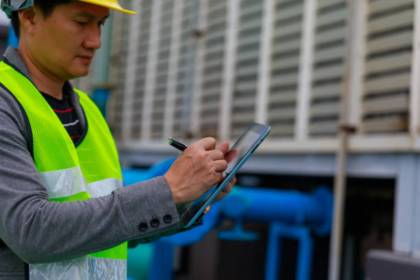istock Asian engineer with safety helmet at the construction site typing on a digital tablet 1338275648