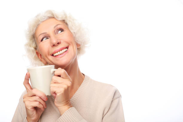 istock old excited lady smiling laughing, holding cup drinking coffee or tea 1338276742