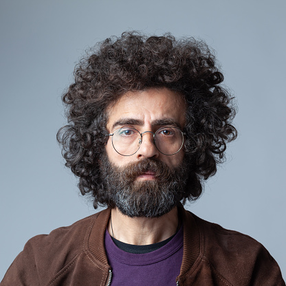 Mugshot portrait of mature adult man with long afro curly hair. Shot in studio with a full frame DSLR camera.