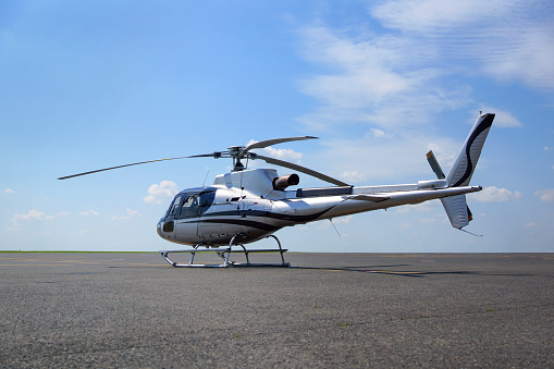 Executive light class helicopter shot on the airport apron. Nice wather. Summer blue sky.