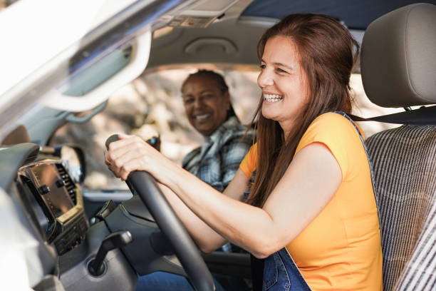 donne multirazziali senior in viaggio con camper - amici maturi che cantano all'interno del mini van mentre guidano per le vacanze nella natura - driving senior adult car women foto e immagini stock