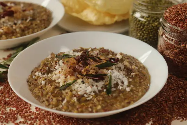 Porridge or gruel made of Navara rice, mung beans and fenugreek seeds sprinkled with fresh grated coconut. Commonly know as navara kichadi or uluva kanji in India. Shot on white background.