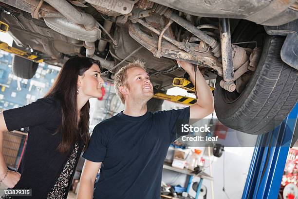 Mujer Mirando Y Mecánico De Reparación De Automóviles Foto de stock y más banco de imágenes de Garaje de reparación