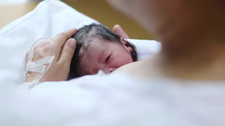 Young beautiful mother, breastfeeding her newborn baby boy at hospital