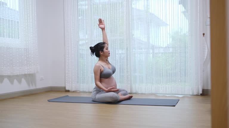 Pregnant Asian mother exercising Yoga in living room