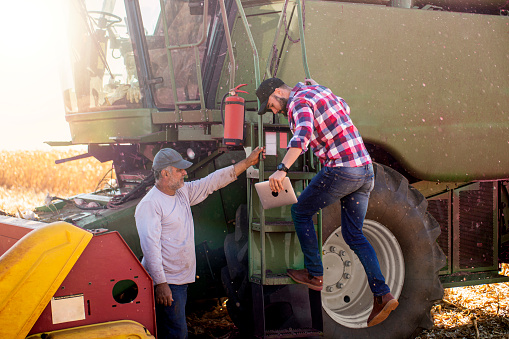 Photo of two men beside a combine harvester.