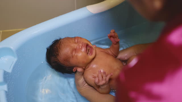 A little newborn baby having a blue bath by mother