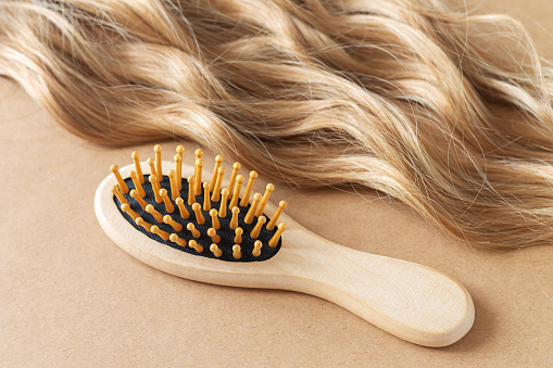 Long blond female wavy hair and bamboo comb brush