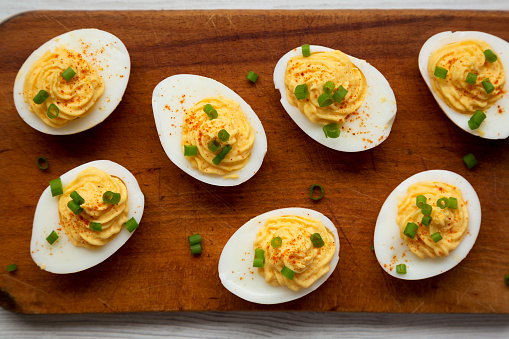 Homemade Deviled Eggs with Chives on a rustic wooden board, top view. Flat lay, overhead, from above.