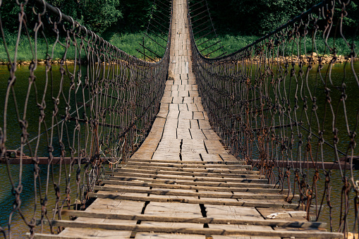 old suspension bridge over the river in the countryside going into perspective