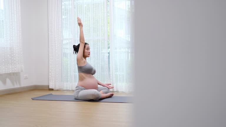 Pregnant Asian mother exercising Yoga in living room