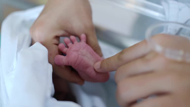 Mother hold her newborn baby foots