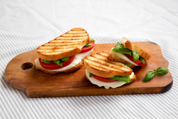 istock Tasty Grilled Caprese Panini (Mozzarella, Tomatoes and Basil) on a rustic wooden board, side view. 1338298739