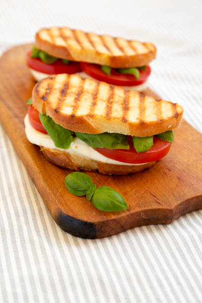 istock Tasty Grilled Caprese Panini (Mozzarella, Tomatoes and Basil) on a rustic wooden board, low angle view. 1338298763