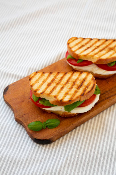 istock Tasty Grilled Caprese Panini (Mozzarella, Tomatoes and Basil) on a rustic wooden board, side view. 1338298773